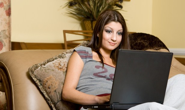Woman browsing social networking websites and checking messages from friends using her laptop